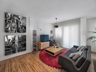 Modern interior decoration of a living room with a sofa, black and white posters, retro lamp, carpet, wooden floor, vintage wood chairs and table.