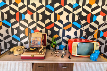 Vintage decoration with geometric wallpaper, retro tv, old portable record player, telephone and...