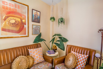 Vintage interior decoration with a retro sofa, magazines,old movies posters,  macrame plant...