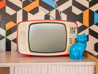 Retro television with vintage wallpaper in the background. Interior decoration ceramic figure from the 70s