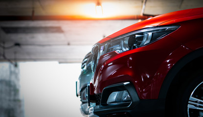 Selective focus on red shiny SUV sport car parked at shopping mall indoor parking lot. Headlamp...