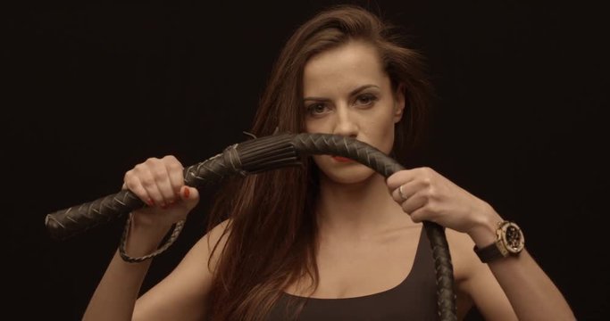 Vampire lady shows her whip and hits by it, female portrait, red lips, feeling bossy.