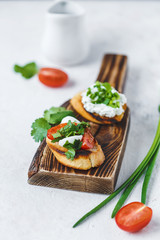 several types of italian bruschetta with tomatoes, mozzarella and herbs on a wooden board on a light background
