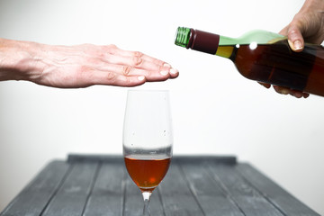 A man shows his hand a refusal to drink wine. 