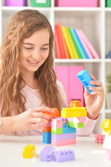 Portrait of curly teen girl playing with colorful plastic blocks