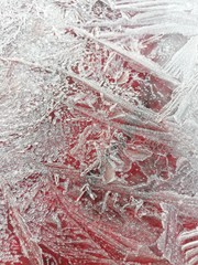 	Thin shiny layer of ice on a red background 