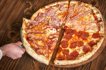 Slice of pizza quattro stagioni on scapula on wooden table