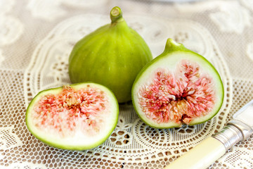 Halved ripe figs and antique kitchen knife close up on antique vintage lace kitchen cloth