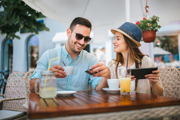 Happy young couple shopping online while sitting in a cafe.
