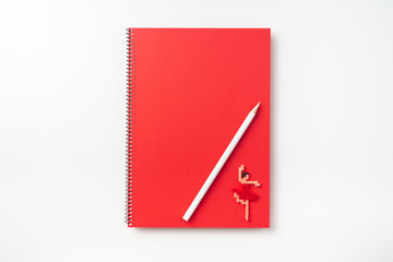 Top view of  red spiral notebook, page, pencil