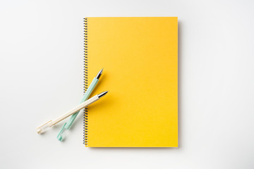 Top view of yellow spiral notebook, page, pencil