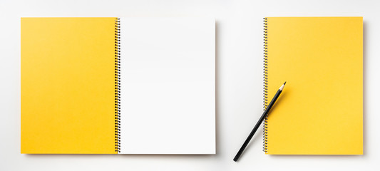 Top view of yellow spiral notebook, page, pencil