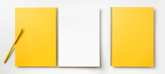 Top view of yellow spiral notebook, page, pencil