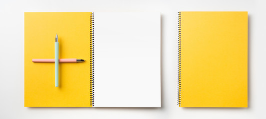 Top view of yellow spiral notebook, page, pencil