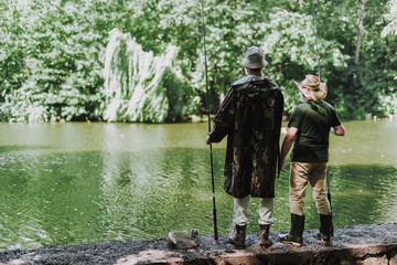 Naklejka premium Full length of male friends anlers standing on the bank of the river while resting outdoors