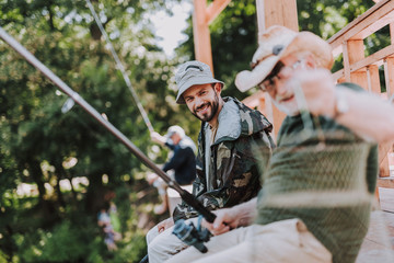 Cheerful bearded man fishing with his father while spending weekend with pleasure