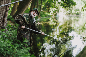 Joyful aged angler enjoying his fishing weekend