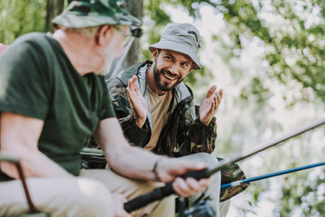 Emotional bearded man fishing with his elderly father