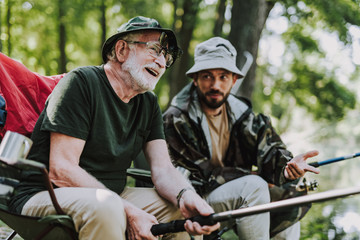 Joyful aged man fishing with his son together