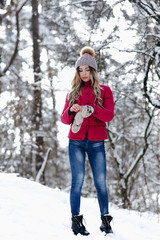 Fototapeta na wymiar Amazing young pretty woman wears knitted gloves. Girl with long blond hair dressed up purple winter coat and ball point cap and blue jeans. Christmas, winter holidays concept. - Image