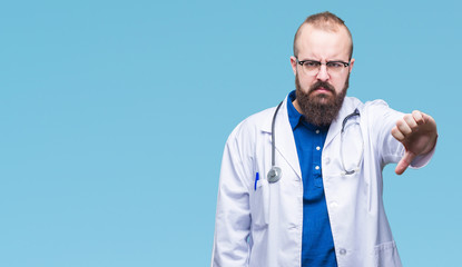 Young caucasian doctor man wearing medical white coat over isolated background looking unhappy and angry showing rejection and negative with thumbs down gesture. Bad expression.