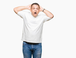 Fototapeta premium Middle age arab man wearig white t-shirt over isolated background Crazy and scared with hands on head, afraid and surprised of shock with open mouth