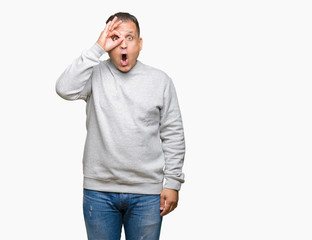 Fototapeta premium Middle age arab man wearing sport sweatshirt over isolated background doing ok gesture shocked with surprised face, eye looking through fingers. Unbelieving expression.