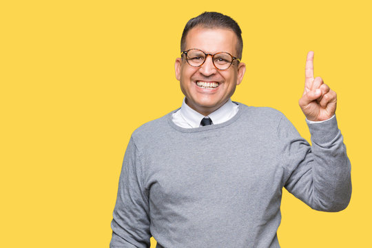 Middle age bussines arab man wearing glasses over isolated background showing and pointing up with finger number one while smiling confident and happy.