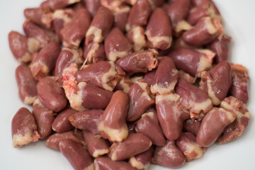 Raw chicken hearts on a white plate