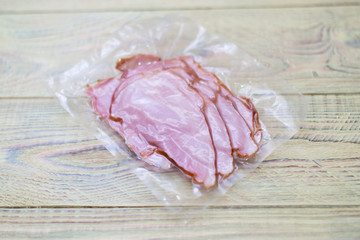 Ham, bacon in the package on a wooden background.