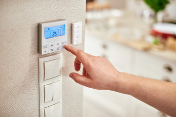 hand adjusting temperature inside house