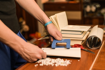 The guy makes holes in a punch paper in a modern office on the background of open books