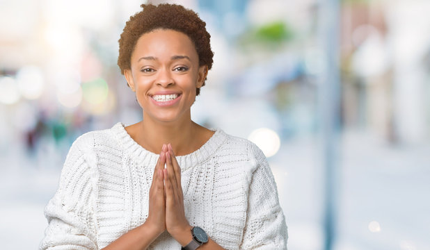 Beautiful young african american woman wearing sweater over isolated background praying with hands together asking for forgiveness smiling confident.