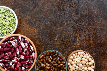 Healthy food, dieting, nutrition concept, vegan protein source. Assortment of colorful raw legumes: green peas, beans, chickpeas in bowls. Background. Free space