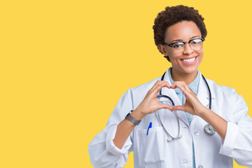 Young african american doctor woman wearing medical coat over isolated background smiling in love showing heart symbol and shape with hands. Romantic concept.