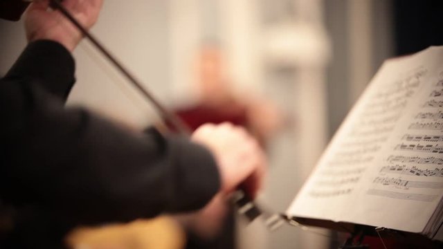 Chamber orchestra. A man standing and playing violin by notes