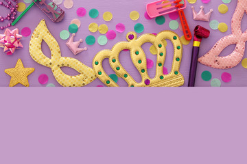 Purim celebration concept (jewish carnival holiday) over purple, pink wooden background. Top view.