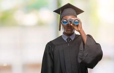 Young graduated african american man looking for a job using binoculars with a confident expression...