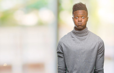 Young african american man over isolated background puffing cheeks with funny face. Mouth inflated with air, crazy expression.