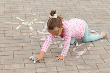 little girl draws a chalk