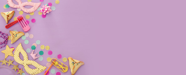 Purim celebration concept (jewish carnival holiday) over purple, pink wooden background. Top view.