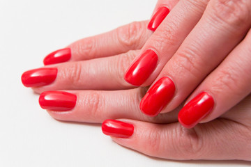 The nails of beautiful female fingers are covered with red varnish.