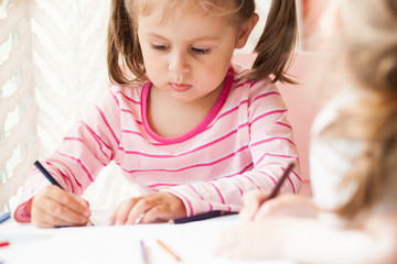 The girl draws in colored pencils