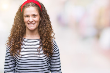 Beautiful brunette curly hair young girl wearing stripes sweater over isolated background with a happy and cool smile on face. Lucky person.