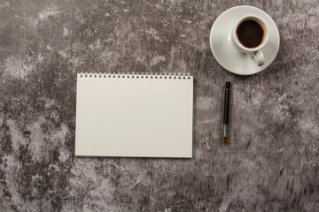 Obraz na płótnie Canvas A mock up of a template table with a blank envelope, notepad and a cup of coffee with stationery in a gray background. View from above. Flat lay. Layout for the designer.