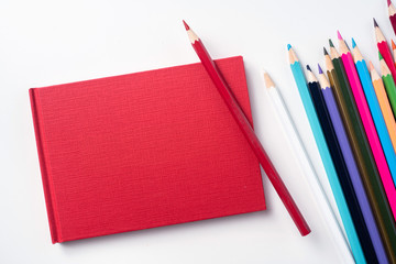 Top view of red hardcover notebook and pencil