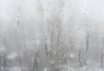  Drops of water on the window pane on the background of the snow-covered city