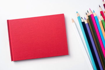 Top view of red hardcover notebook and pencil