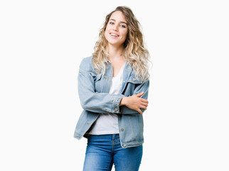 Beautiful young blonde woman wearing denim jacket over isolated background happy face smiling with crossed arms looking at the camera. Positive person.