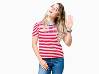 Beautiful young blonde woman over isolated background Waiving saying hello happy and smiling, friendly welcome gesture